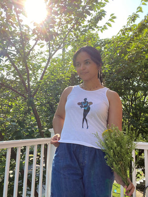 A girl holding flowers and posing in shorts and a white upcycled tank top with an image of supermodel Adut Akech on it