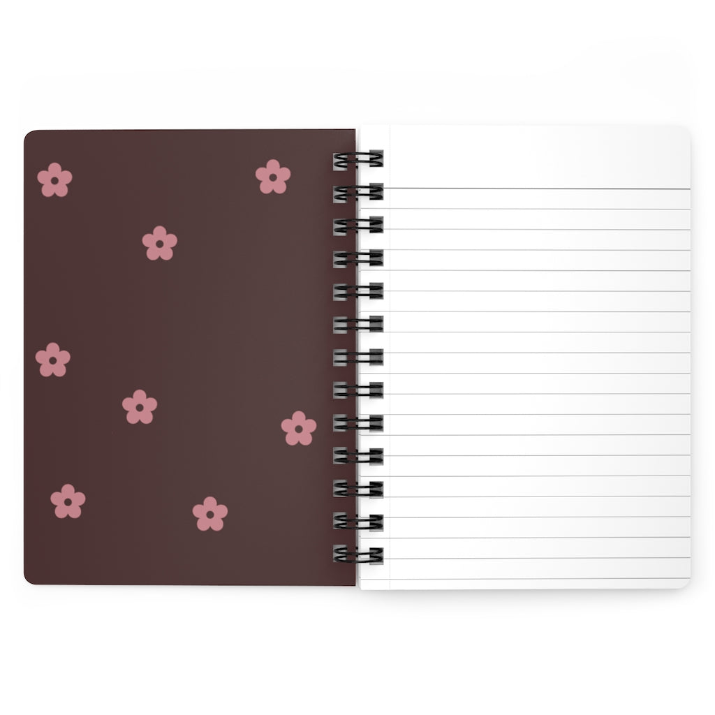 The dark pink inside cover of a spiral journal with small light pink flowers printed on it