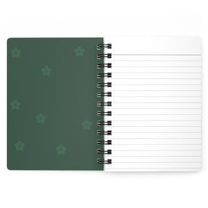 The dark green inside cover of a spiral journal with small light green flowers printed on it