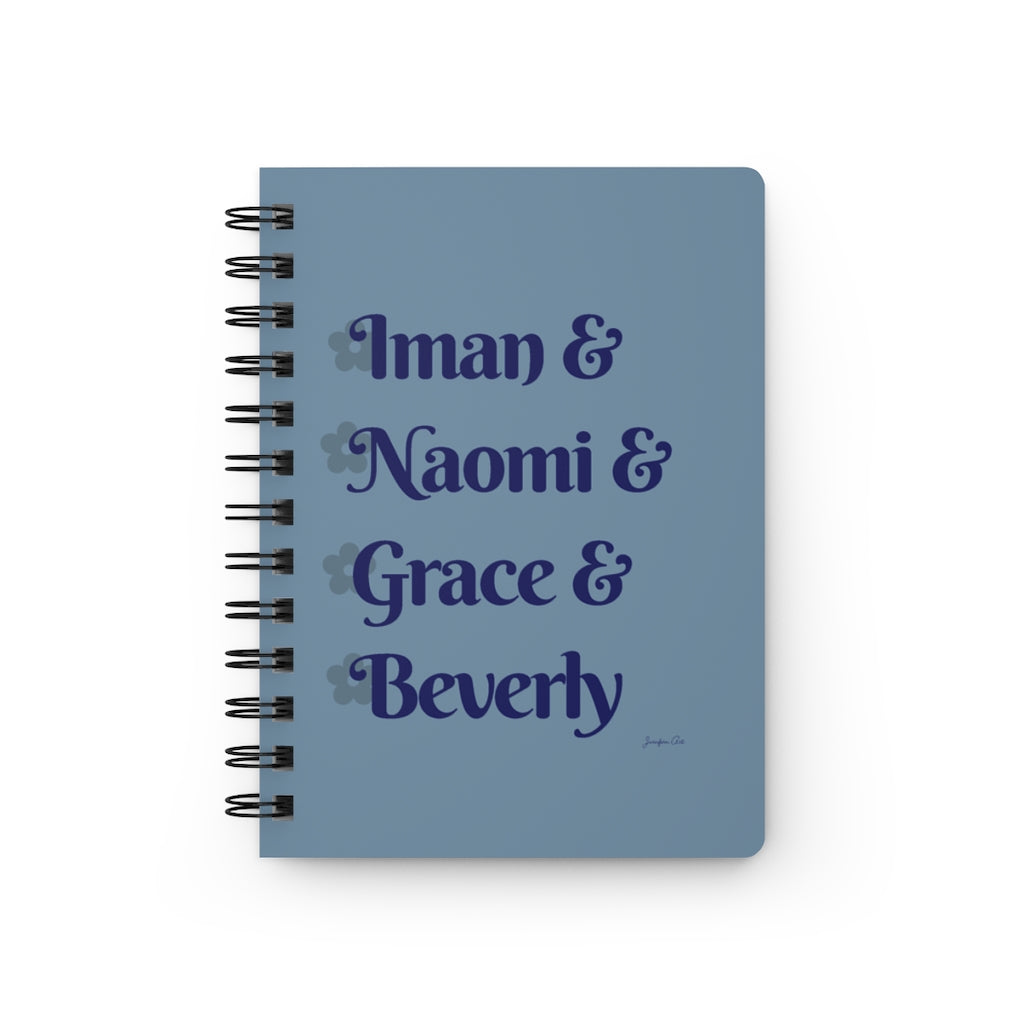 A light blue notebook with dark blue text that reads "Iman & Naomi & Grace & Beverly" in reference to the Black models Iman Abdulmajid, Naomi Campbell, Grace Jones, and Beverly Johnson