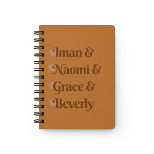 An orange notebook with dark orange text that reads "Iman & Naomi & Grace & Beverly" in reference to the Black models Iman Abdulmajid, Naomi Campbell, Grace Jones, and Beverly Johnson