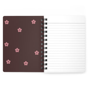 The dark pink inside cover of a spiral journal with small light pink flowers printed on it