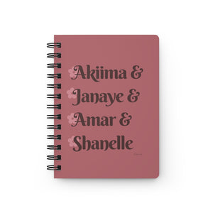 A pink notebook with dark pink text that reads "Akiima & Janaye & Amar & Shanelle" in reference to the Black models Akiima Ajak, Janaye Furman, Amar Akway, and Shanelle Nyasiase