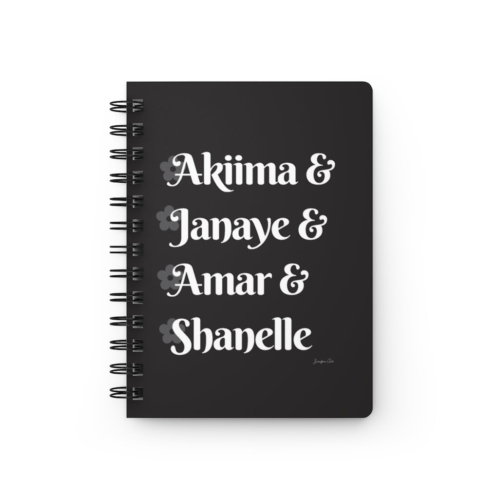 A black notebook with white text that reads "Akiima & Janaye & Amar & Shanelle" in reference to the Black models Akiima Ajak, Janaye Furman, Amar Akway, and Shanelle Nyasiase