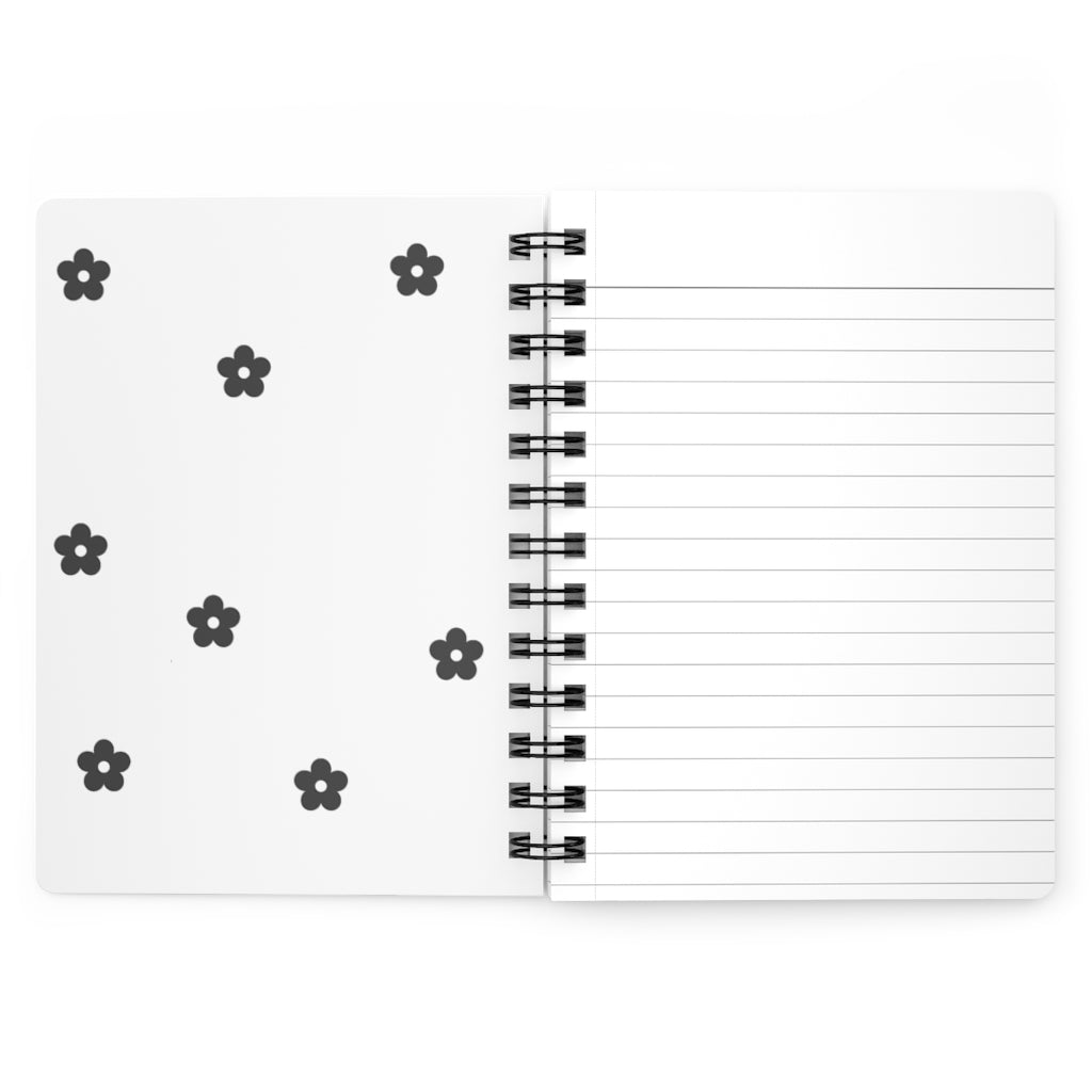 The white inside cover of a spiral journal with small black flowers printed on it