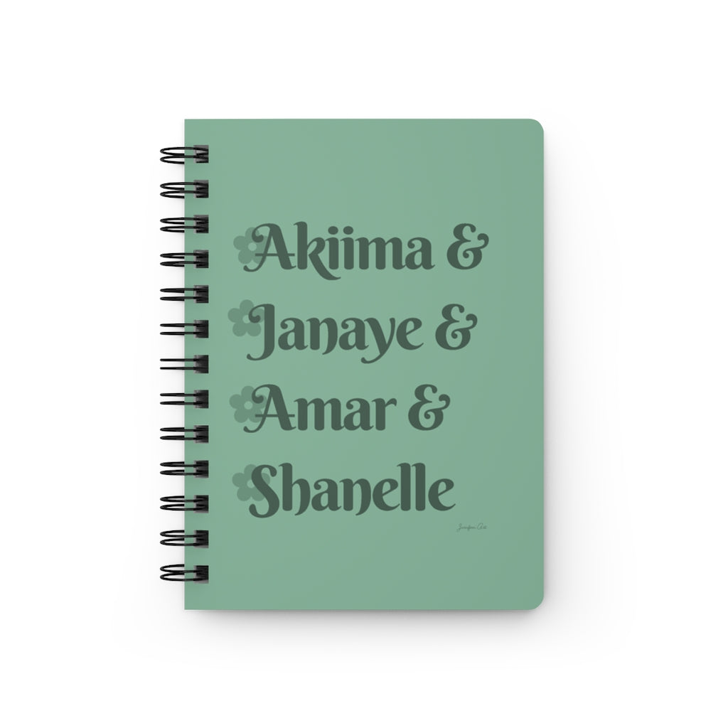 A light green notebook with dark green text that reads "Akiima & Janaye & Amar & Shanelle" in reference to the Black models Akiima Ajak, Janaye Furman, Amar Akway, and Shanelle Nyasiase