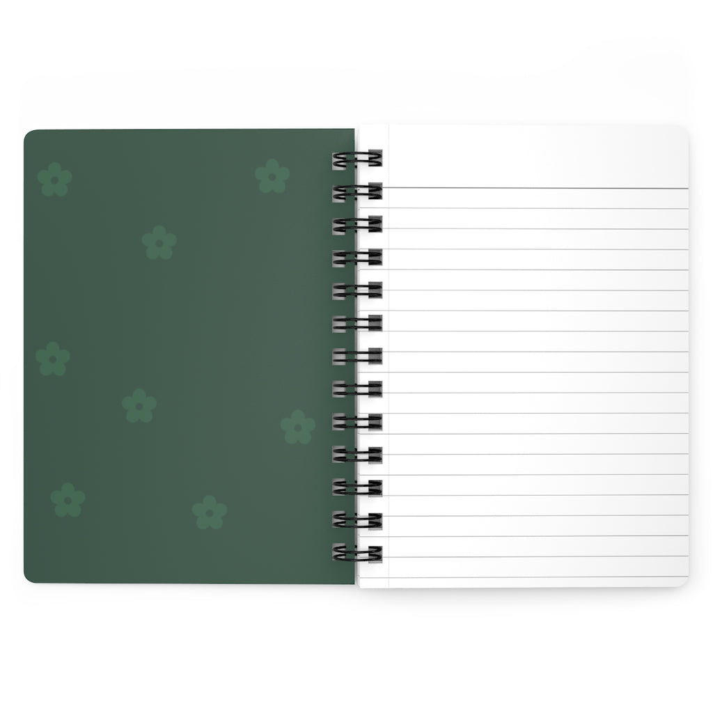 The dark green inside cover of a spiral journal with small light green flowers printed on it