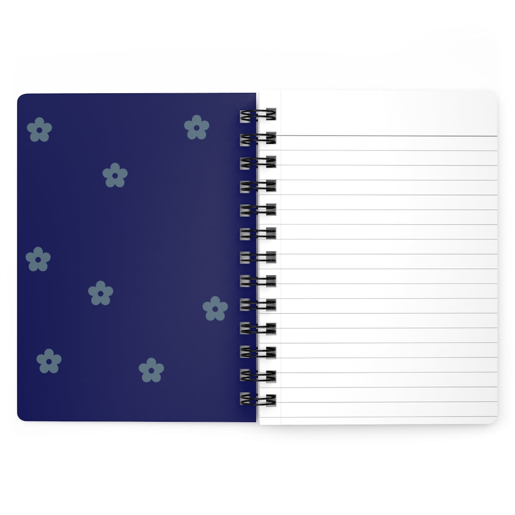 The dark blue inside cover of a spiral journal with small light blue flowers printed on it