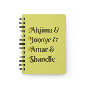 A yellow notebook with dark yellow text that reads "Akiima & Janaye & Amar & Shanelle" in reference to the Black models Akiima Ajak, Janaye Furman, Amar Akway, and Shanelle Nyasiase