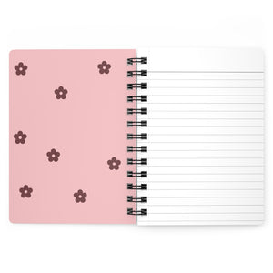 The light pink inside cover of a spiral journal with small dark red flowers printed on it