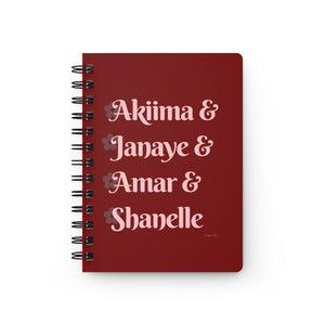 A red notebook with light pink text that reads "Akiima & Janaye & Amar & Shanelle" in reference to the Black models Akiima Ajak, Janaye Furman, Amar Akway, and Shanelle Nyasiase