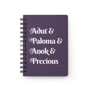 A lavender notebook with white text that reads "Adut & Paloma & Anok & Precious" in reference to the Black models Adut Akech, Paloma Elsesser, Anok Yai, and Precious Lee