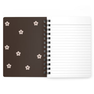 The brown inside cover of a spiral journal with small light beige flowers printed on it