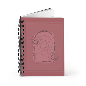 A monochrome pink spiral journal with a line drawing on the cover of a Black woman with an afro surrounded by flowers and text that reads "Forever Inspired by Black Beauty"