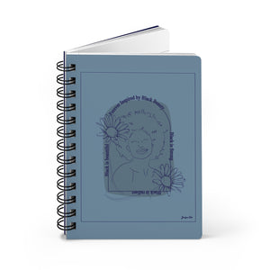 A monochrome blue spiral journal with a line drawing on the cover of a Black woman with an afro surrounded by flowers and text that reads "Forever Inspired by Black Beauty"