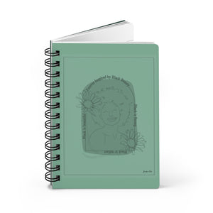 A monochrome green spiral journal with a line drawing on the cover of a Black woman with an afro surrounded by flowers and text that reads "Forever Inspired by Black Beauty"