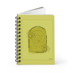 A monochrome yellow spiral journal with a line drawing on the cover of a Black woman with an afro surrounded by flowers and text that reads "Forever Inspired by Black Beauty"