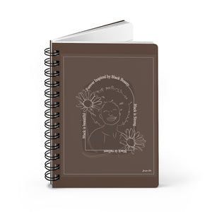 A monochrome brown spiral journal with a line drawing on the cover of a Black woman with an afro surrounded by flowers and text that reads "Forever Inspired by Black Beauty"