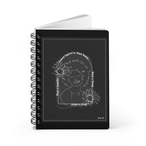 A monochrome spiral journal with a line drawing on the cover of a Black woman with an afro surrounded by flowers and text that reads "Forever Inspired by Black Beauty"