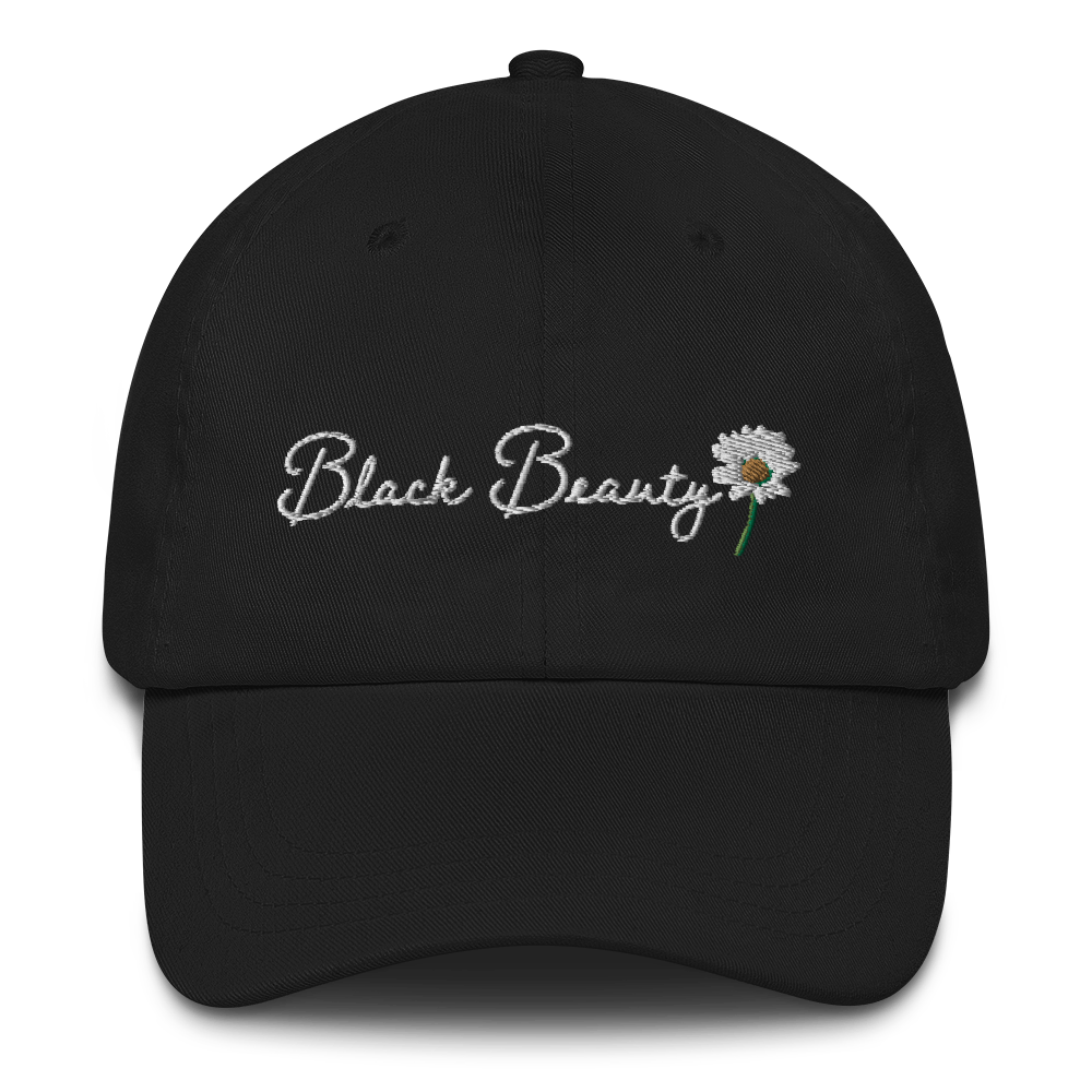 A black baseball cap with white cursive embroidered text that reads "Black Beauty" with an embroidered daisy