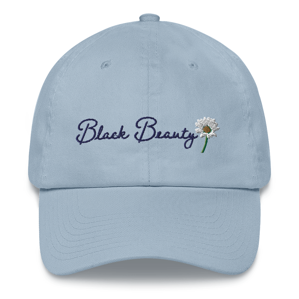 A light blue baseball cap with dark blue cursive embroidered text that reads "Black Beauty" with an embroidered daisy