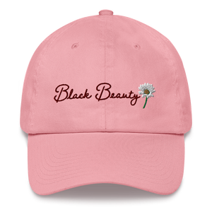 A light pink baseball cap with dark pink cursive embroidered text that reads "Black Beauty" with an embroidered daisy