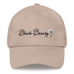 A beige baseball cap with black cursive embroidered text that reads "Black Beauty" with an embroidered daisy