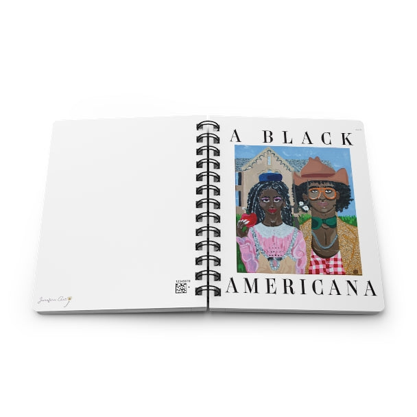 A spiral journal with a painting on the front cover reminiscent of the classic American Gothic, but with a Black couple wearing 'rural' outfits by Gucci and black text that reads “A Black Americana.”