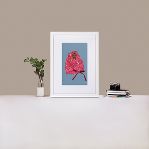 A white framed print with white board matting, with an illustration of Black supermodel Adut Akech wearing a pink Valentino gown with a bow on it, with a light blue background, standing up on a table next to a green plant and a stack of books