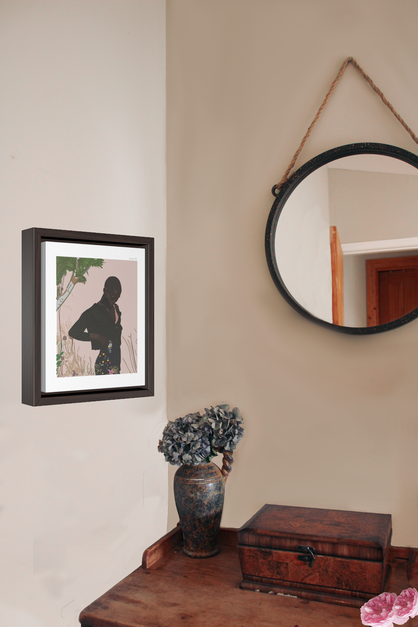 A framed canvas illustration of Black model Amar Akway posing in a garden in a Miu Miu outfit, hanging on a wall next to a wood desk and a hanging circle mirror
