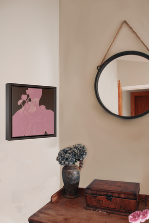 A framed canvas illustration of a monochrome pink portrait of a woman holding a vase of flowers, hanging on wall next to a hanging circle mirror and a dark wood desk